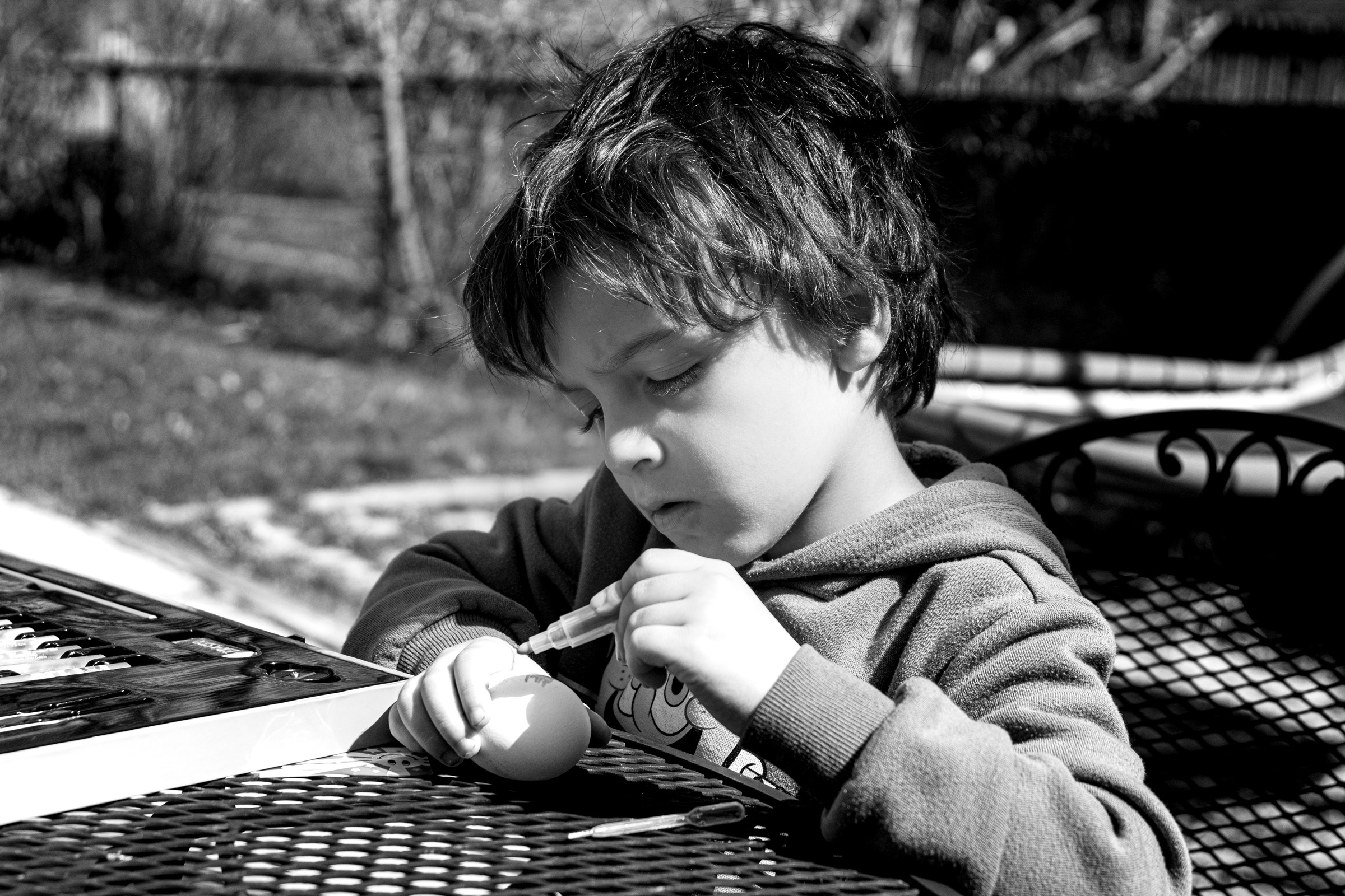 He carefully paints an Easter egg
